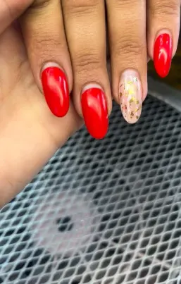 Unhas vermelhas com uma unha decorada com folha de ouro