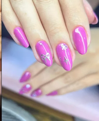 Unhas amendoadas em magenta com laço e estrelas em glitter